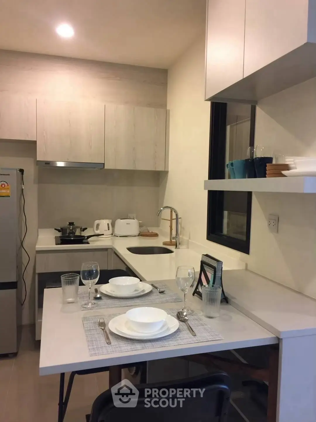 Modern kitchen with sleek cabinetry and dining setup in a cozy apartment.