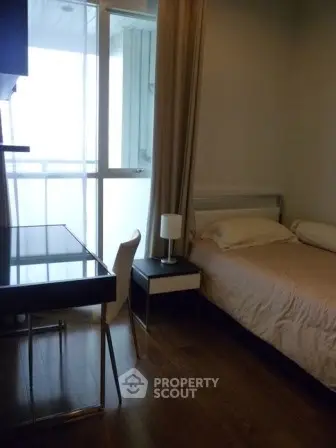 Cozy bedroom with a single bed and study desk, featuring a window with natural light.