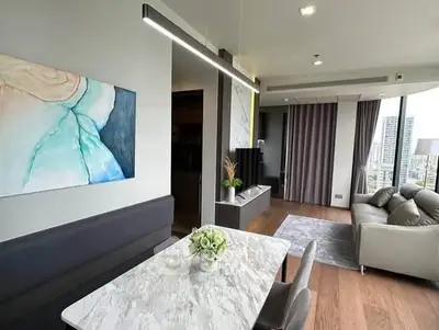 Modern living room with elegant decor and city view, featuring a marble dining table and cozy seating area.