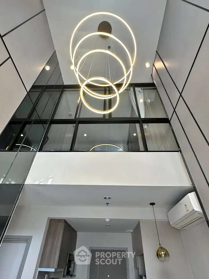 Modern high-ceiling interior with stylish lighting and glass balcony