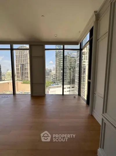 Spacious modern living room with floor-to-ceiling windows and stunning city view.