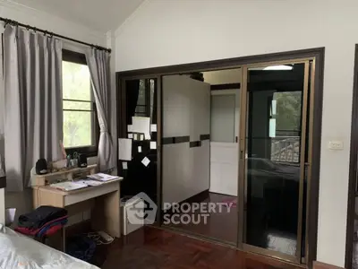 Cozy bedroom with study desk and sliding wardrobe doors, natural light from windows