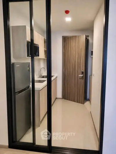 Modern compact kitchen with sleek appliances and wooden cabinetry in a stylish apartment.