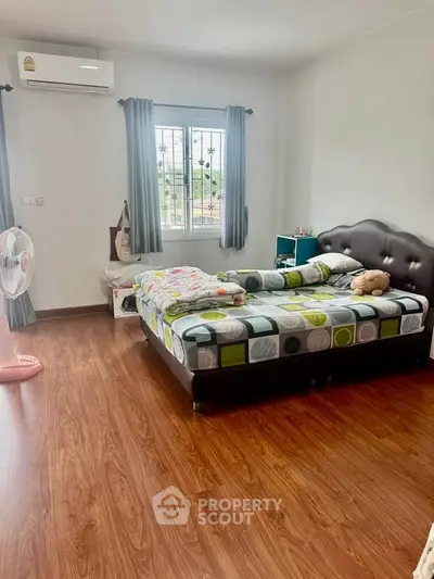 Spacious bedroom with wooden flooring and modern decor