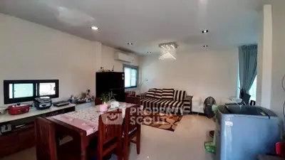 Spacious living room with modern decor and ample natural light, featuring a cozy dining area and stylish furniture.