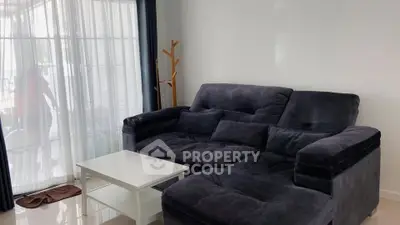 Cozy living room with plush sofa and natural light through sheer curtains.