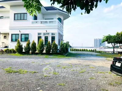 Charming white house with lush garden and ample parking space, offering serene suburban living.