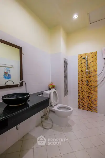 Modern bathroom with stylish sink and vibrant shower tiles.