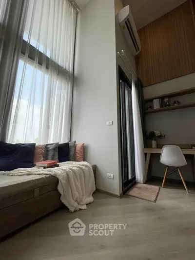 Modern living room with high ceilings, large windows, and cozy seating area.