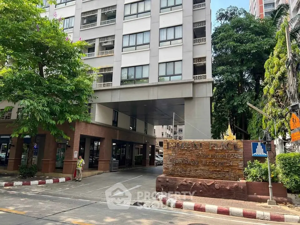 Modern apartment building entrance with lush greenery and clear signage.