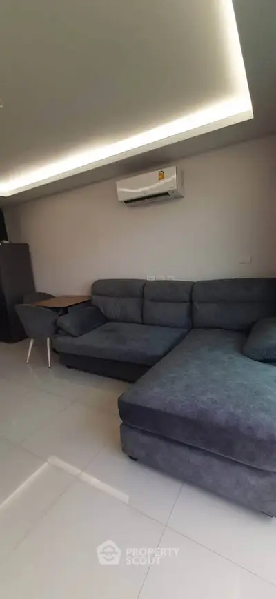 Modern living room with sleek sectional sofa and air conditioning unit, perfect for relaxation.