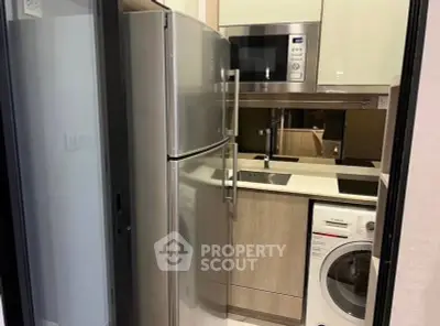 Compact modern kitchen with stainless steel appliances and washing machine