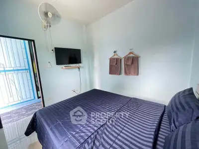 Cozy bedroom with modern decor and wall-mounted TV, perfect for relaxation.