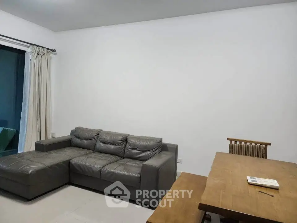 Spacious living room with modern gray sofa and wooden dining table, perfect for family gatherings.