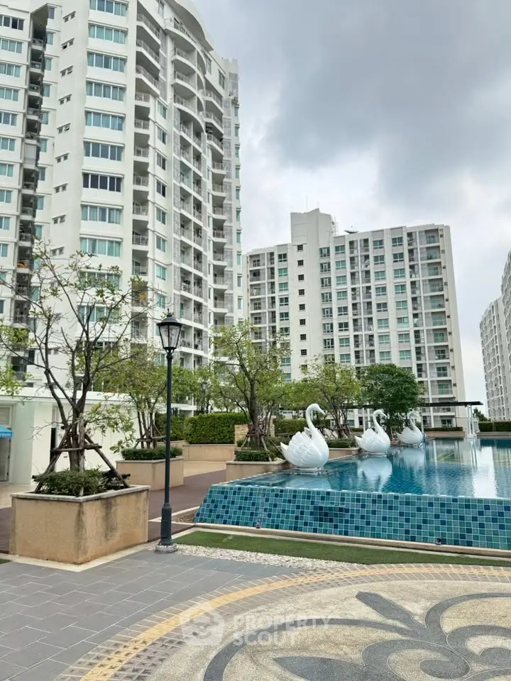 Luxurious residential complex with modern high-rise buildings and elegant pool area featuring swan sculptures.