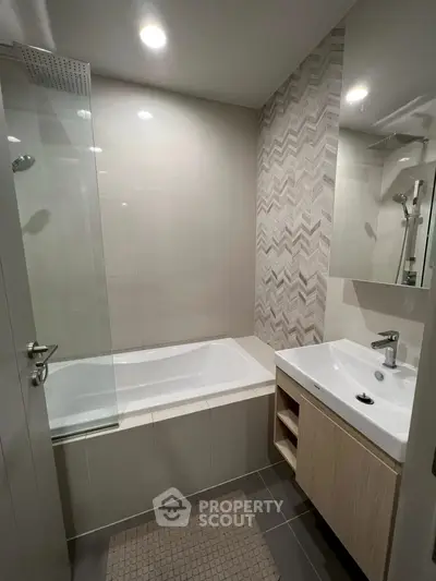 Modern bathroom with stylish tile design and integrated bathtub in a contemporary apartment.