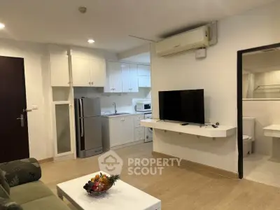Modern open-layout living room with kitchen, featuring air conditioning and sleek appliances.