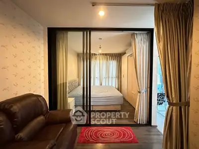 Modern apartment with cozy living room and stylish bedroom separated by glass sliding doors.