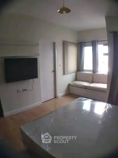 Cozy bedroom with natural light, wall-mounted TV, and comfortable seating area.