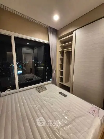 Modern bedroom with city view, featuring built-in closet and large window.