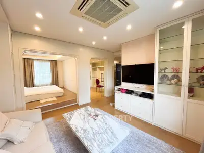 Spacious living room with modern decor and adjacent bedroom, featuring elegant marble coffee table.