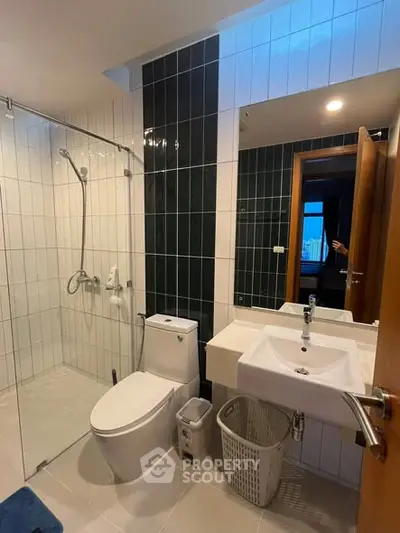 Modern bathroom with glass shower and sleek fixtures in contemporary apartment.
