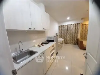Modern kitchen with sleek cabinets and cozy dining area in open layout apartment.