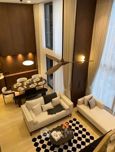 Luxurious high-ceiling living room with elegant decor and dining area, featuring floor-to-ceiling windows.