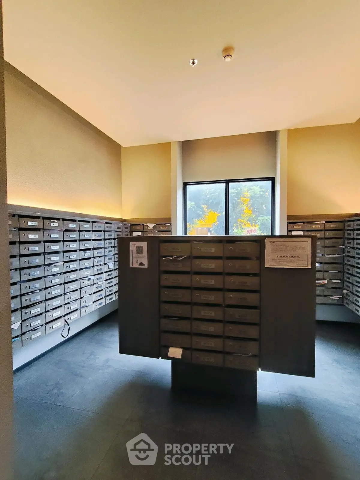 Modern apartment building mailroom with organized mailboxes and natural lighting.