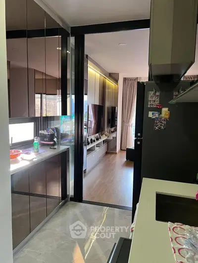 Modern kitchen with sleek cabinets leading to a stylish living room with natural light.