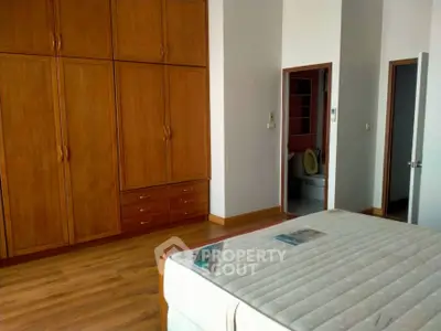Spacious bedroom with wooden wardrobe and comfortable bed, ideal for cozy living.