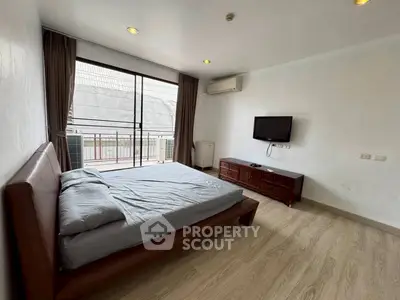 Spacious bedroom with modern furnishings and balcony access in a stylish apartment.