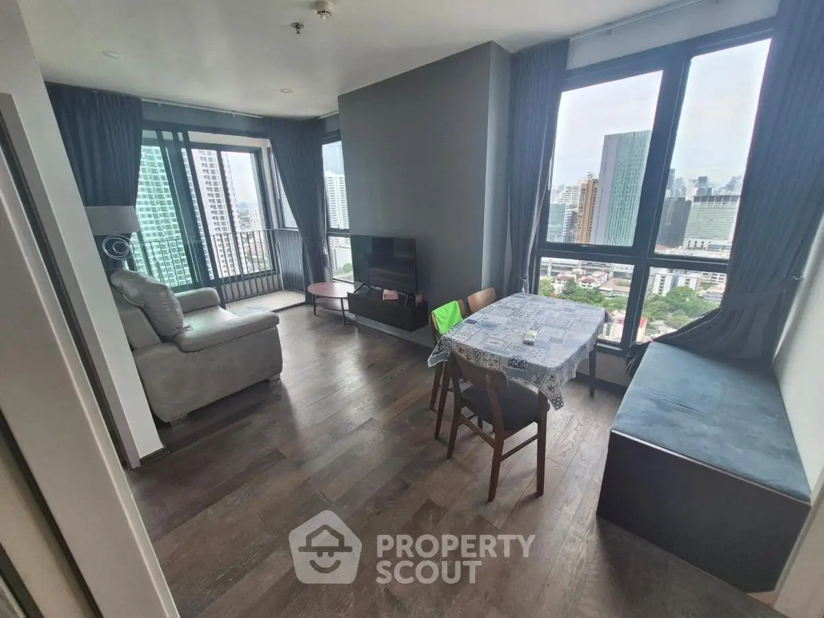 Spacious living room with panoramic city views and modern furnishings in a high-rise apartment.
