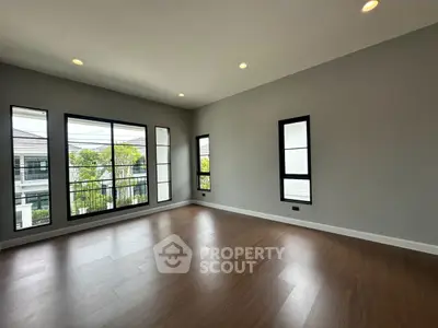 Spacious empty room with large windows and wooden flooring, perfect for customization.
