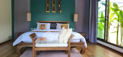 Luxurious bedroom with elegant decor and large window overlooking lush greenery.