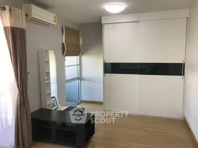 Spacious bedroom with modern sliding wardrobe and natural light.