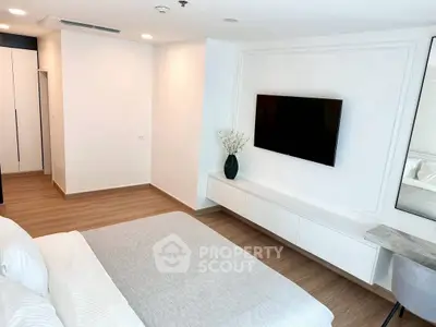 Modern bedroom with sleek design, wall-mounted TV, and minimalist decor in a bright apartment.