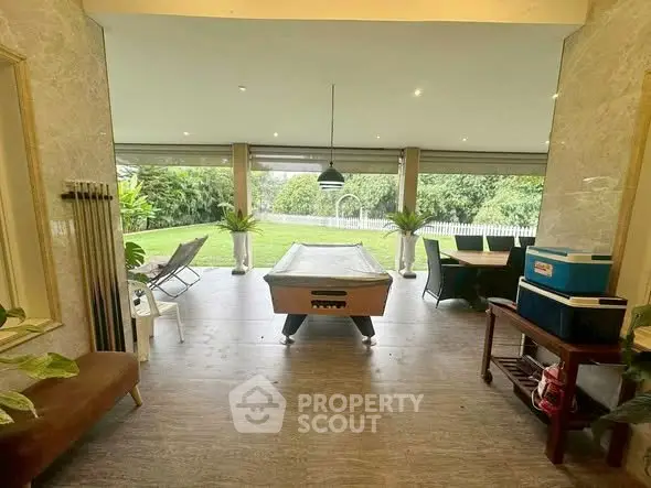 Spacious outdoor entertainment area with pool table and garden view, perfect for leisure and relaxation.