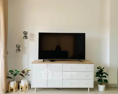 Modern living room with sleek TV stand, stylish decor, and indoor plants for a cozy ambiance.