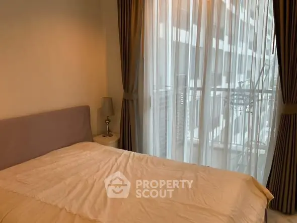 Cozy bedroom with large window and elegant curtains in modern apartment.