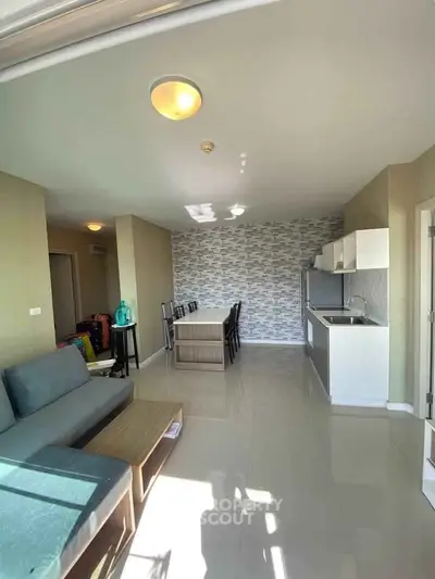 Spacious living room with modern open kitchen and dining area, featuring stylish decor and ample natural light.