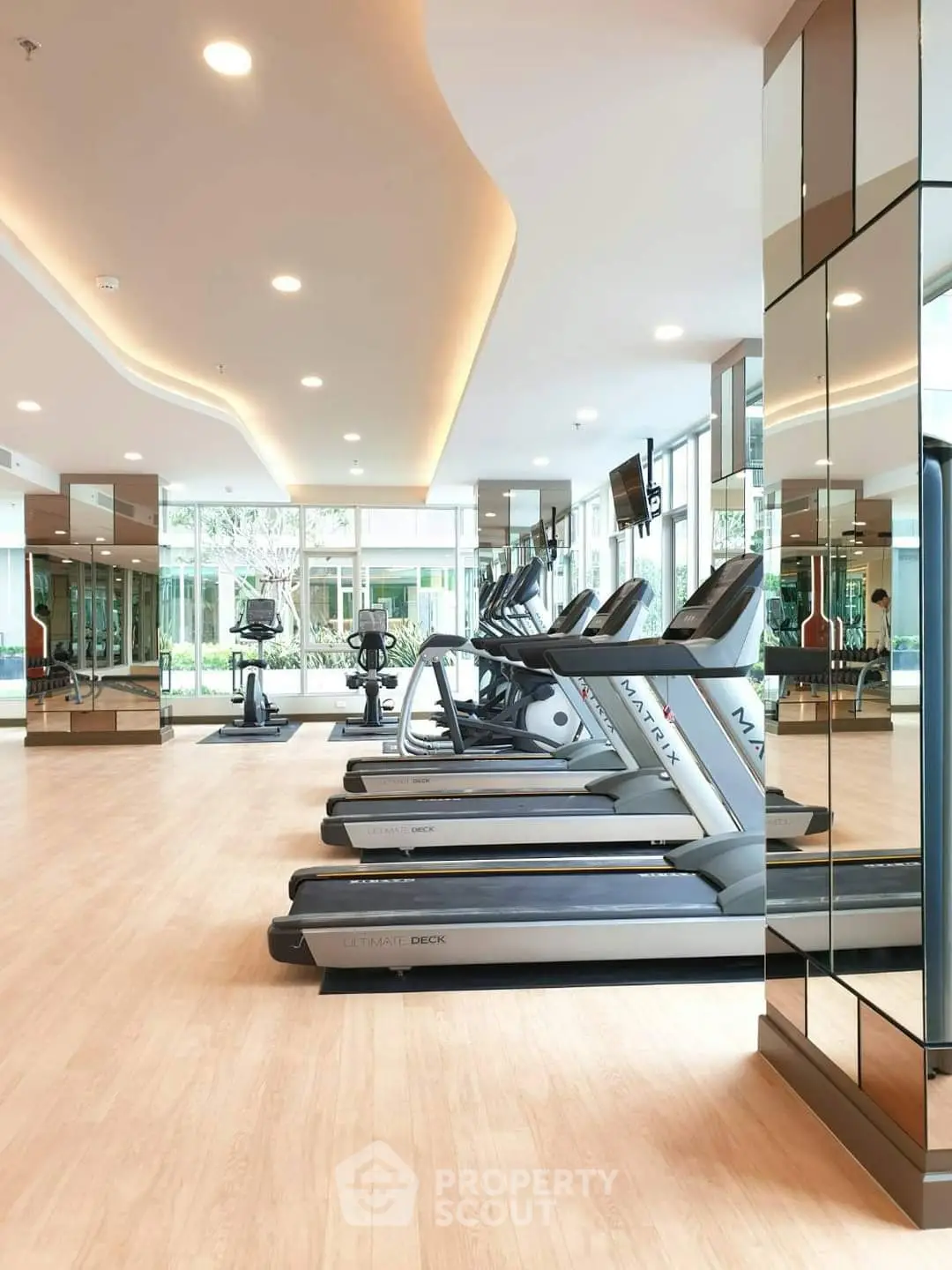 Modern gym with treadmills and exercise bikes in a bright, mirrored space.
