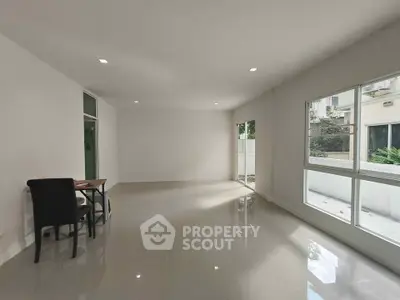 Spacious modern living room with large windows and glossy tiled floors