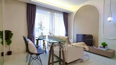 Modern living room with stylish decor, glass table, and large window with elegant curtains.