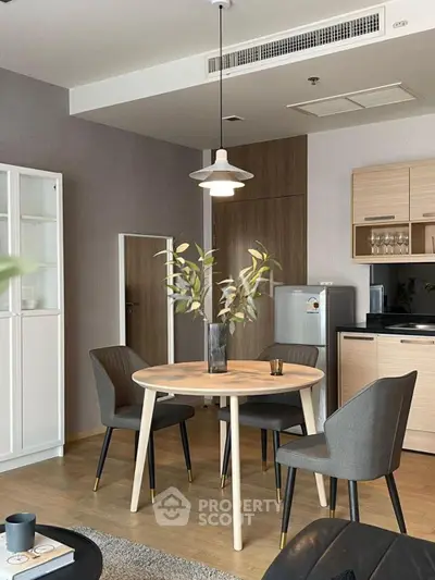 Modern dining area with stylish round table and chairs, adjacent to a sleek kitchen setup.