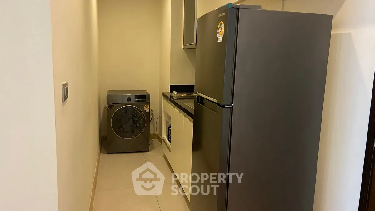 Modern utility room with washing machine and refrigerator in sleek design.
