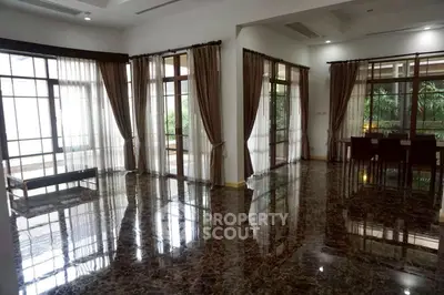 Spacious living room with marble floors and large windows offering garden views.