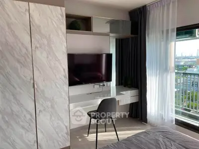 Modern bedroom with stylish decor and city view balcony, featuring a sleek desk and wall-mounted TV.