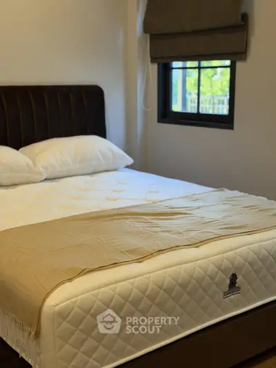 Cozy bedroom with a plush bed and window view, perfect for relaxation.