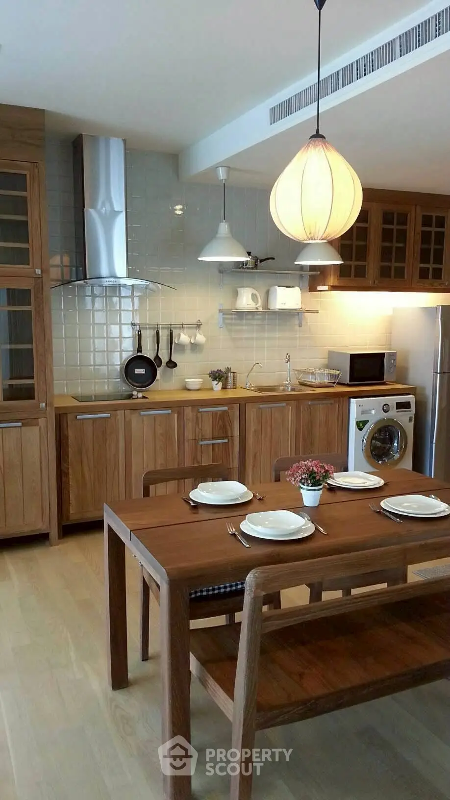 Charming kitchen with wooden cabinets and dining table, featuring modern appliances and cozy lighting.